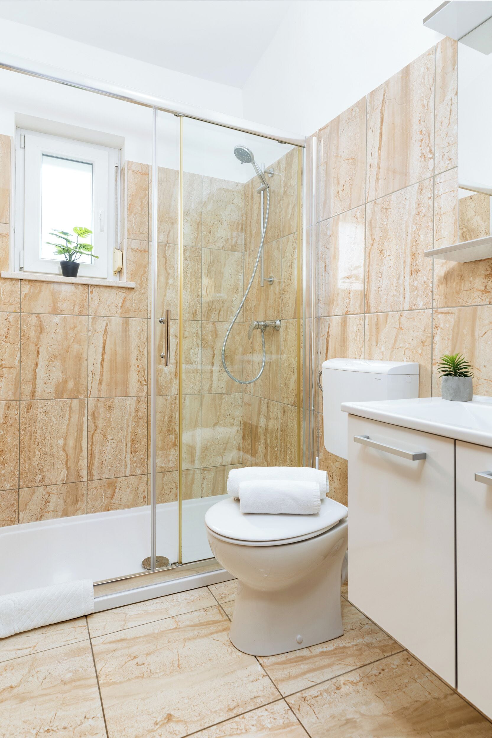 A modern bathroom with a glass-enclosed shower, a toilet, and a sink with a countertop.