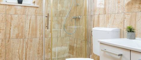 A modern bathroom with a glass-enclosed shower, a toilet, and a sink with a countertop.