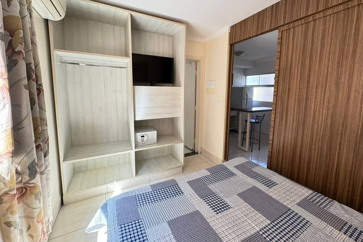 A bedroom with a bed, a wardrobe, a television, and a bathroom door.