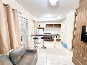 Un espacio habitable pequeño con kitchenette, sofá y televisor.