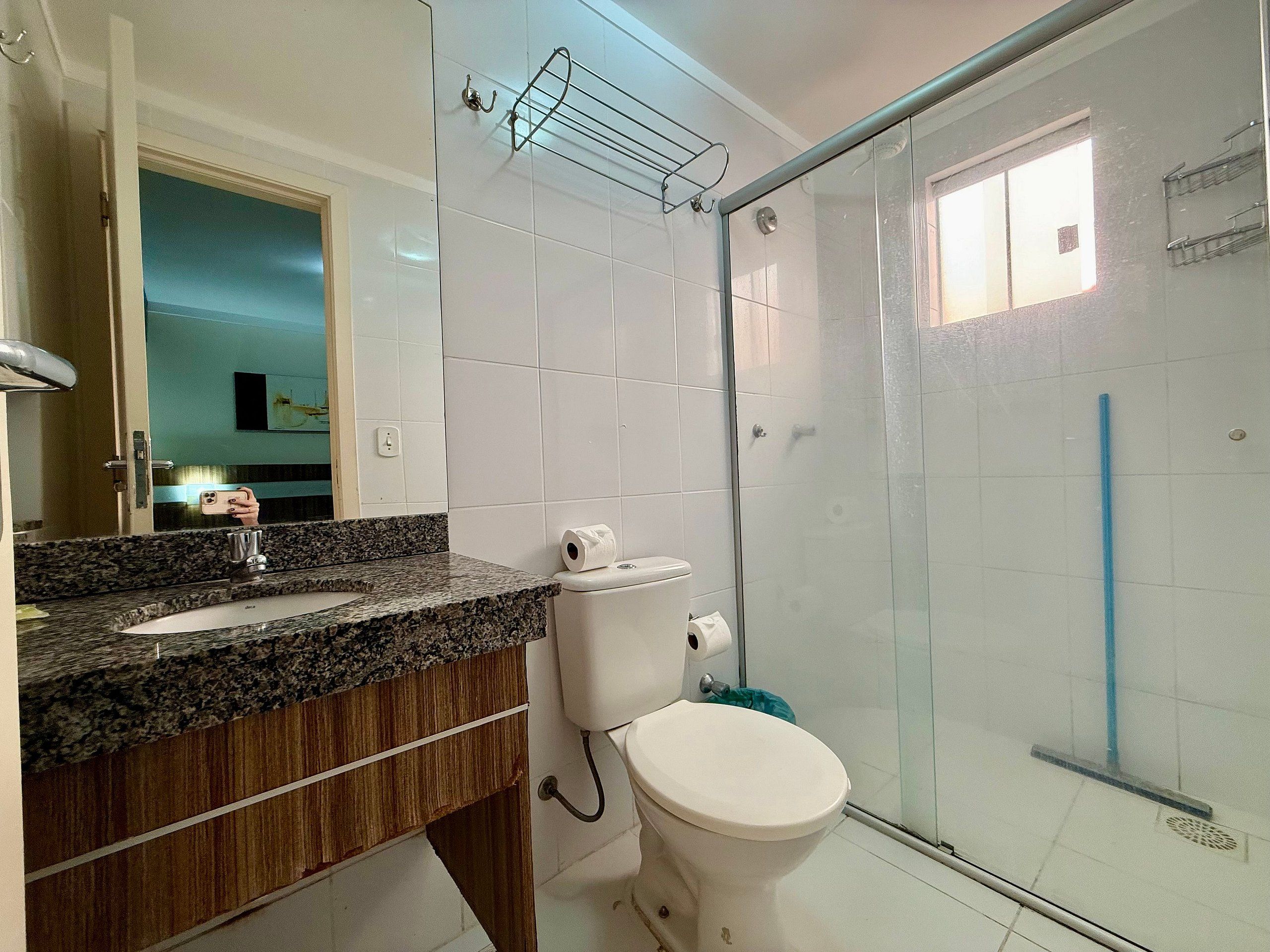 Un baño con encimera de granito, inodoro blanco y cabina de ducha con mampara de vidrio.