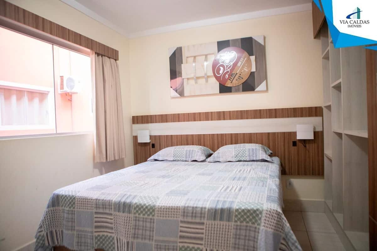 A bedroom with a bed, a window with curtains, a wall clock, and a storage unit.