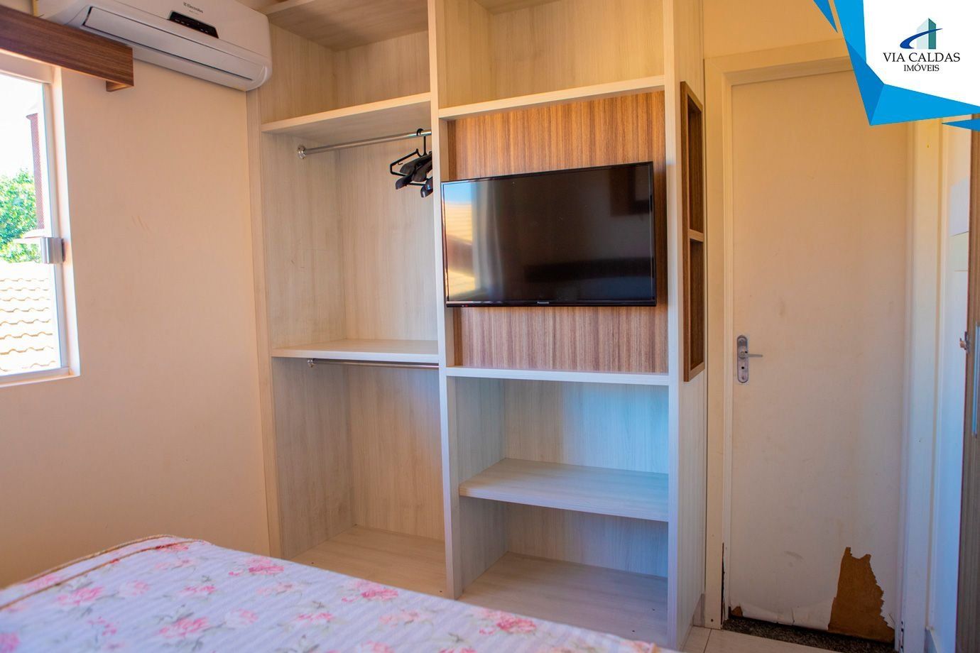 Un dormitorio con cama, armario y televisor.