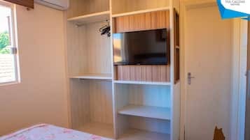 Un dormitorio con cama, armario y televisor.