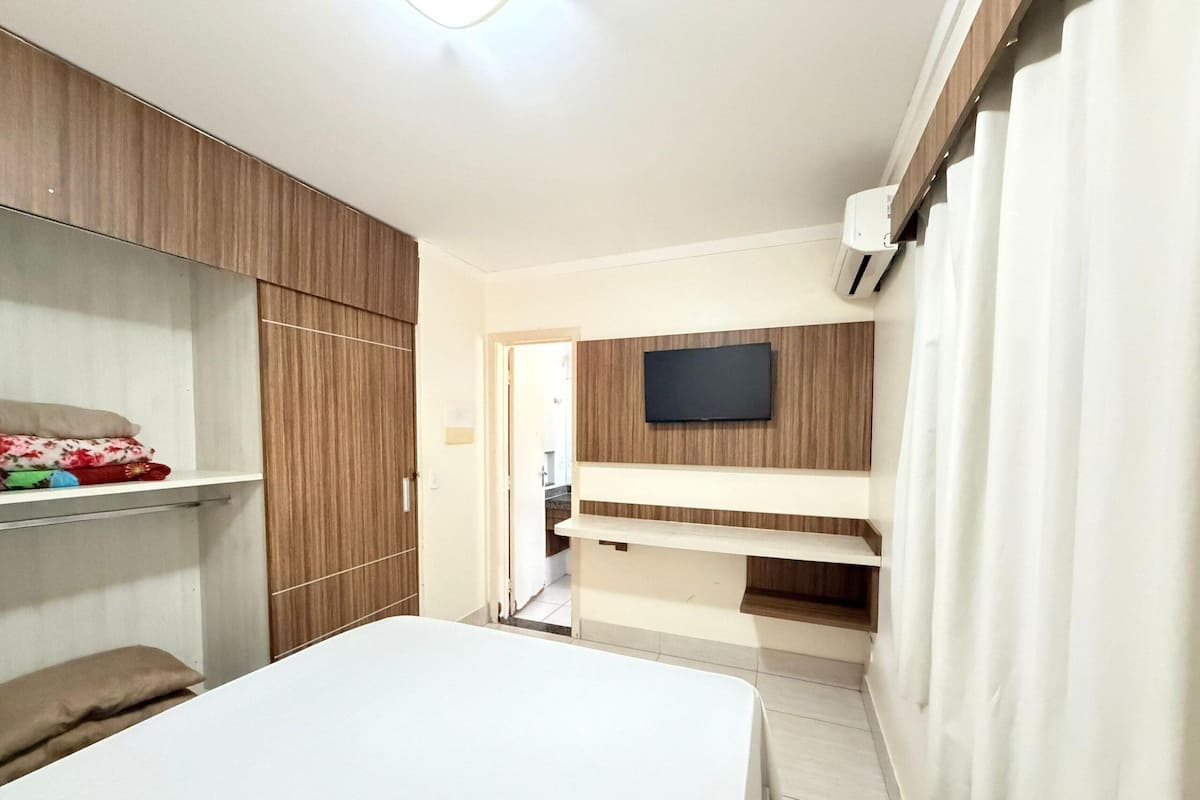 A bedroom with a bed, wardrobe, and a mounted TV.