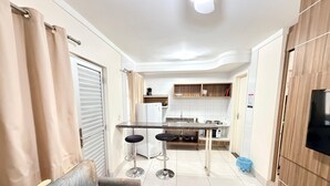 Un espacio habitable pequeño con kitchenette, sofá y televisor.