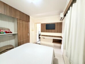 Une chambre à coucher avec un lit, une armoire et un téléviseur fixé au mur.