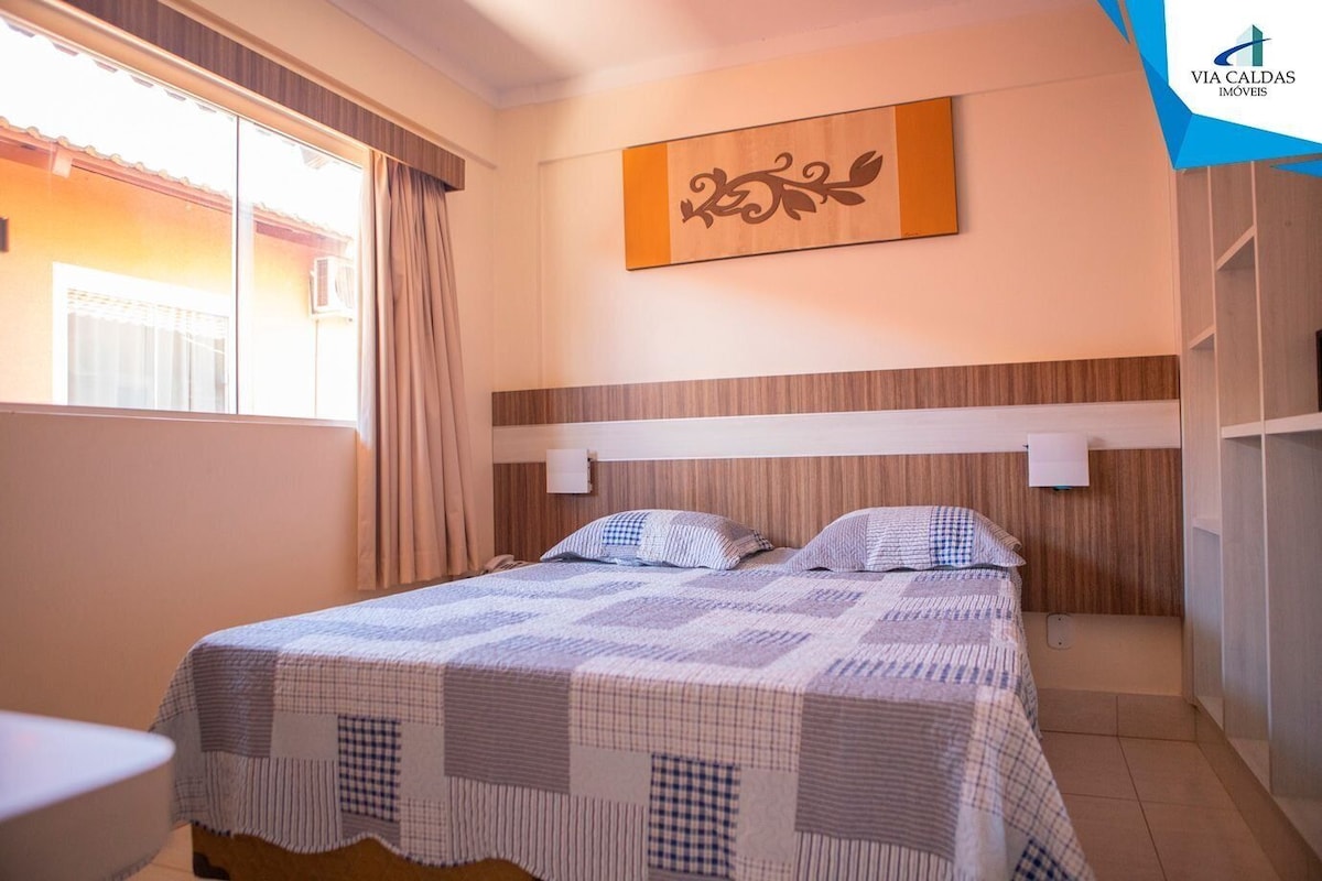 Un dormitorio con cama, ventana con cortinas, un cuadro colgado en la pared y una puerta a la vista.