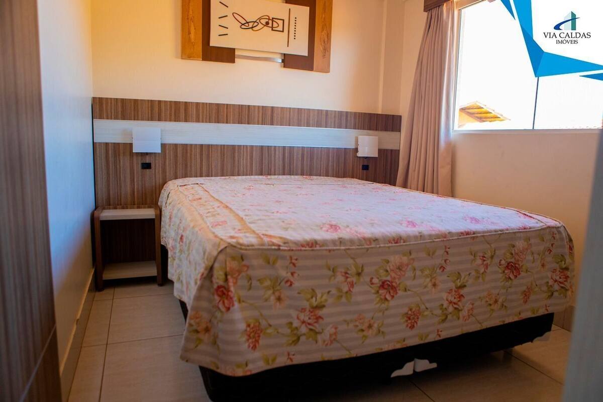 A hotel room with a bed, a nightstand, a wall clock, and a window with curtains.
