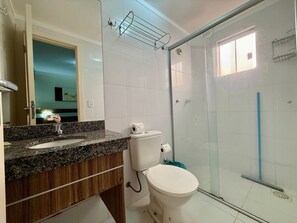 Un bany amb taulell de granat, un vàter blanc i una dutxa amb envà.