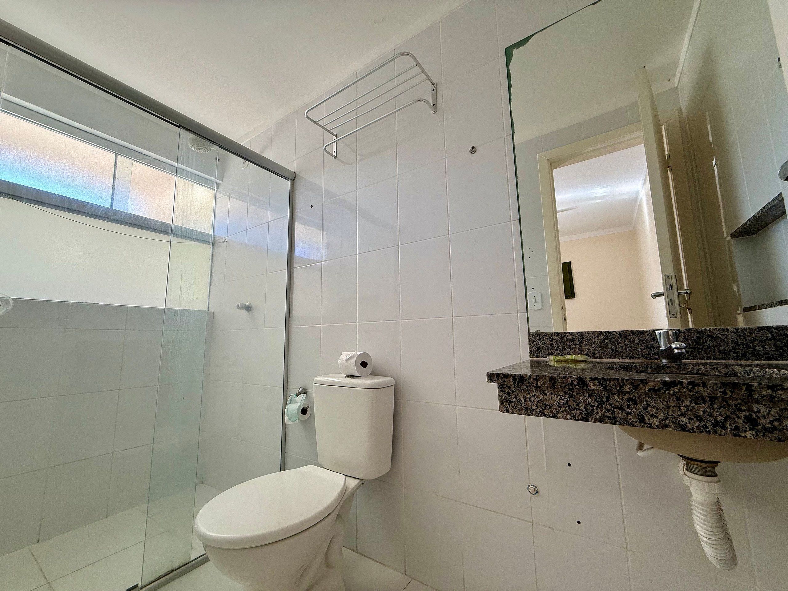 Ein Badezimmer mit Toilette, Dusche und Waschbecken mit Spiegel.