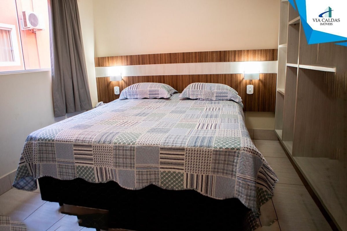 Un dormitorio con cama, dos lámparas de noche, una ventana con cortinas y un armario.