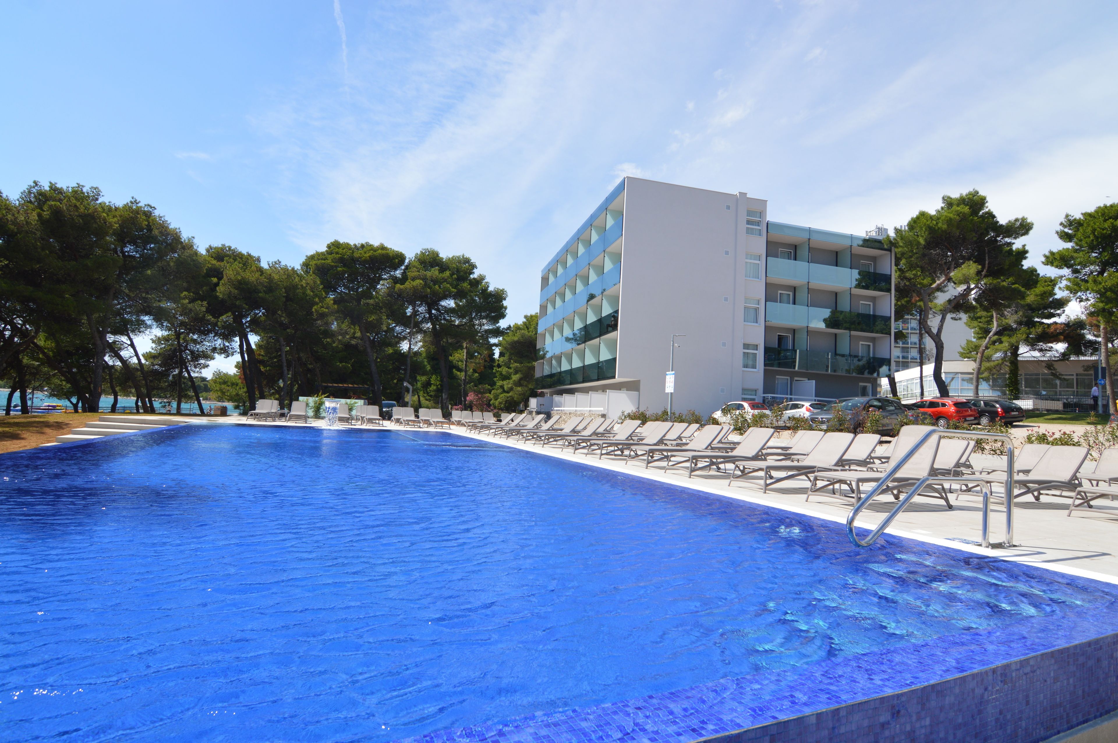 Una piscina con lettini e un edificio moderno sullo sfondo.