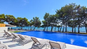 Una piscina con sillones de descanso y vistas al mar.