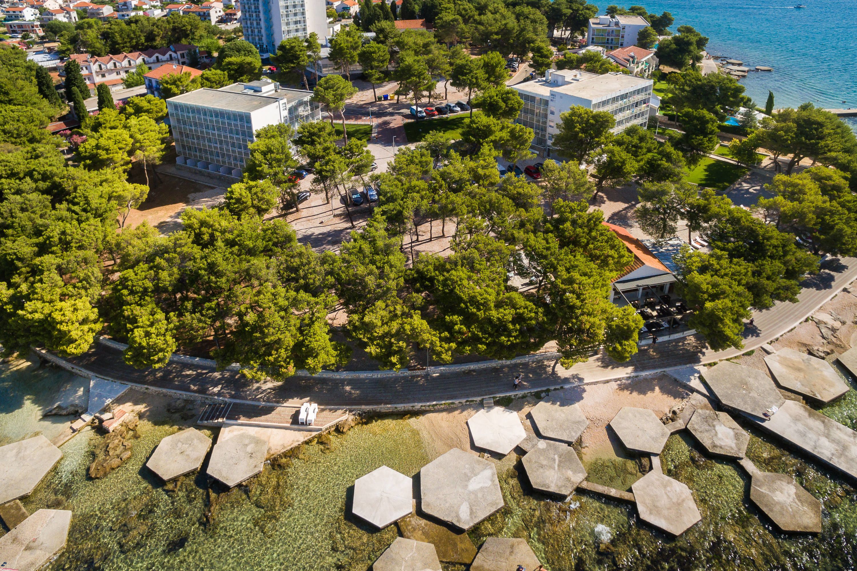 Vista aérea de una zona costera con edificios, árboles y una orilla marítima.