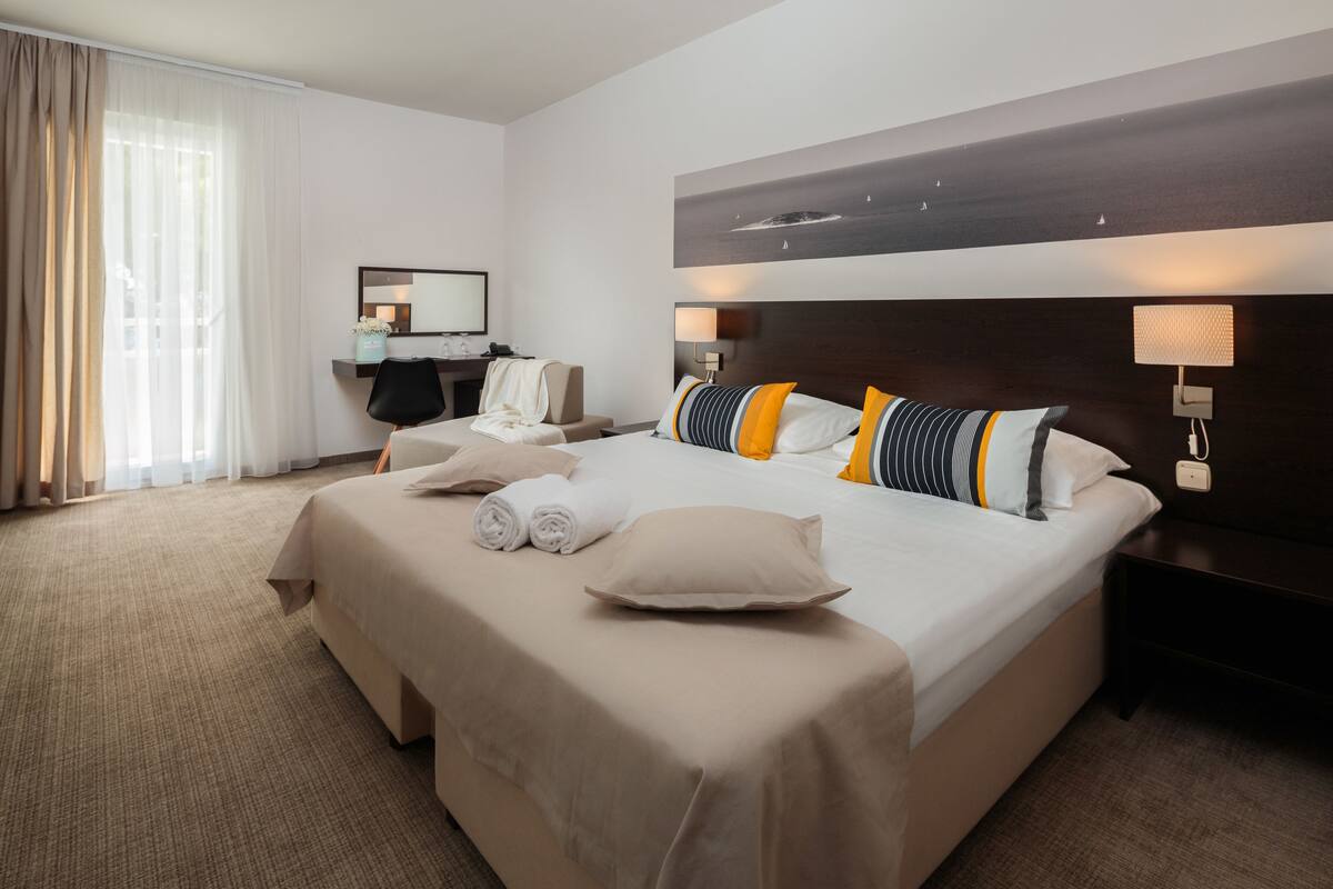 Una habitación de hotel con una cama grande, un escritorio, una silla y una mesita de noche.