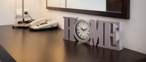 A wooden desk with a clock and a lamp, a mirror, and a 'HOME' sign.