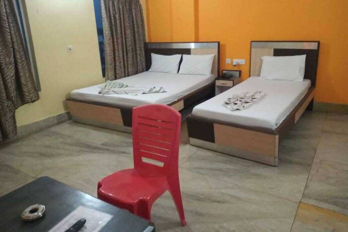 Une chambre d’hôtel avec deux lits, une chaise rouge, une petite table et une table de chevet.