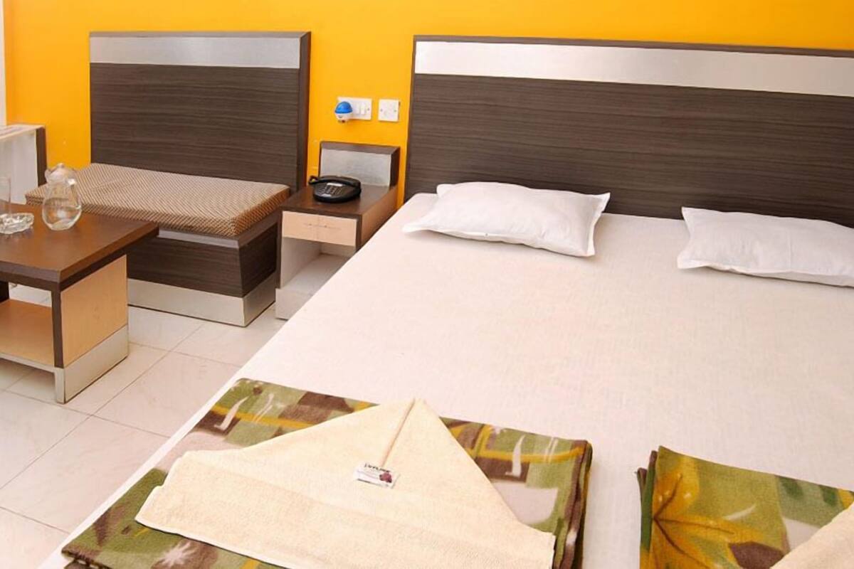Une chambre d’hôtel comprenant un lit, une table de chevet et un petit bureau avec une chaise.