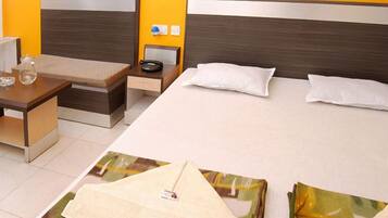 A hotel room with a bed, bedside table, and a small desk with a chair.