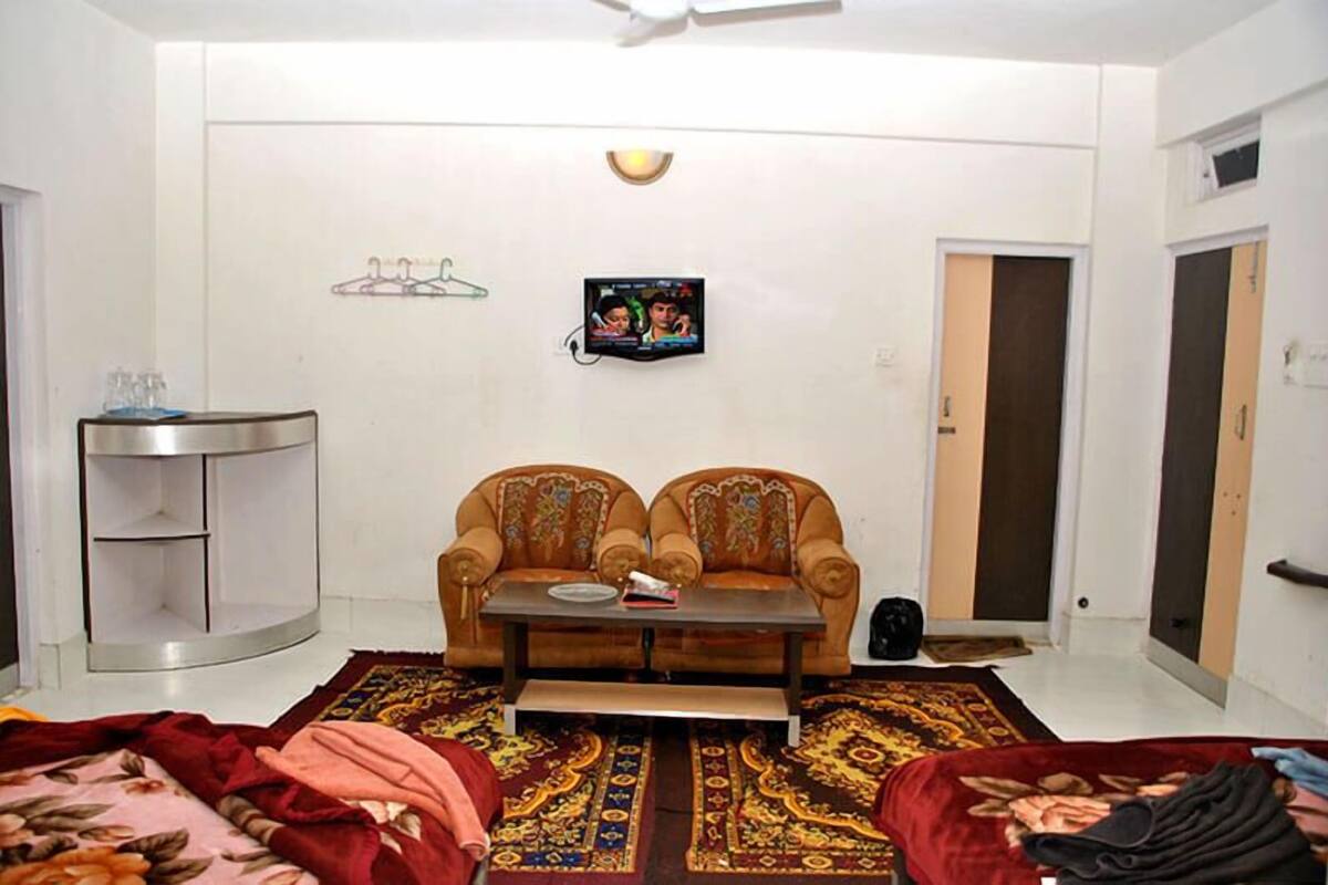 Un salon comprenant un canapé, une table basse, un téléviseur, un petit meuble et un tapis à motifs.