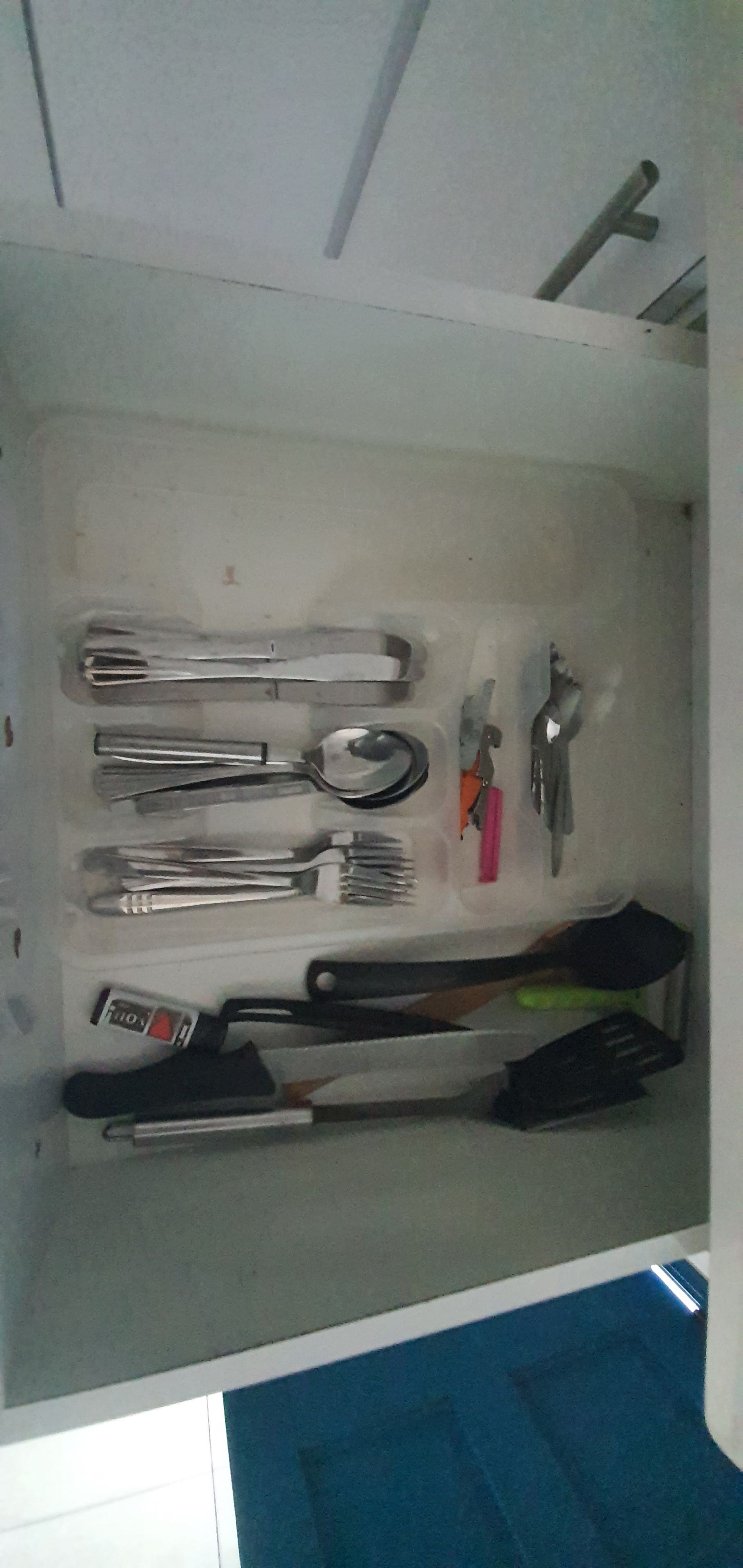 A drawer containing various utensils including forks, knives, and a spoon.