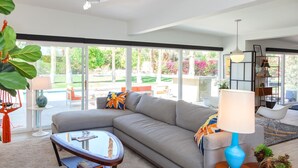 A modern living room with a grey sofa, a round coffee table, and a blue lamp. - Nestled in the Cove (Rancho Mirage)
