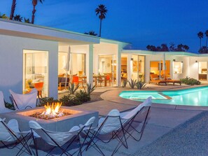 A modern outdoor pool area with a fire feature, seating, and a dining area. - Spero Estate (Palm Springs)