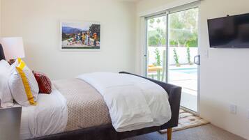A bedroom with a bed, a TV, a painting, and a view of a pool.