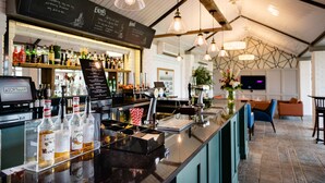 A bar area with a selection of liquor bottles, a chalkboard menu, and a digital display. - The Stratford Park Hotel & Golf Club (Stratford-upon-Avon)