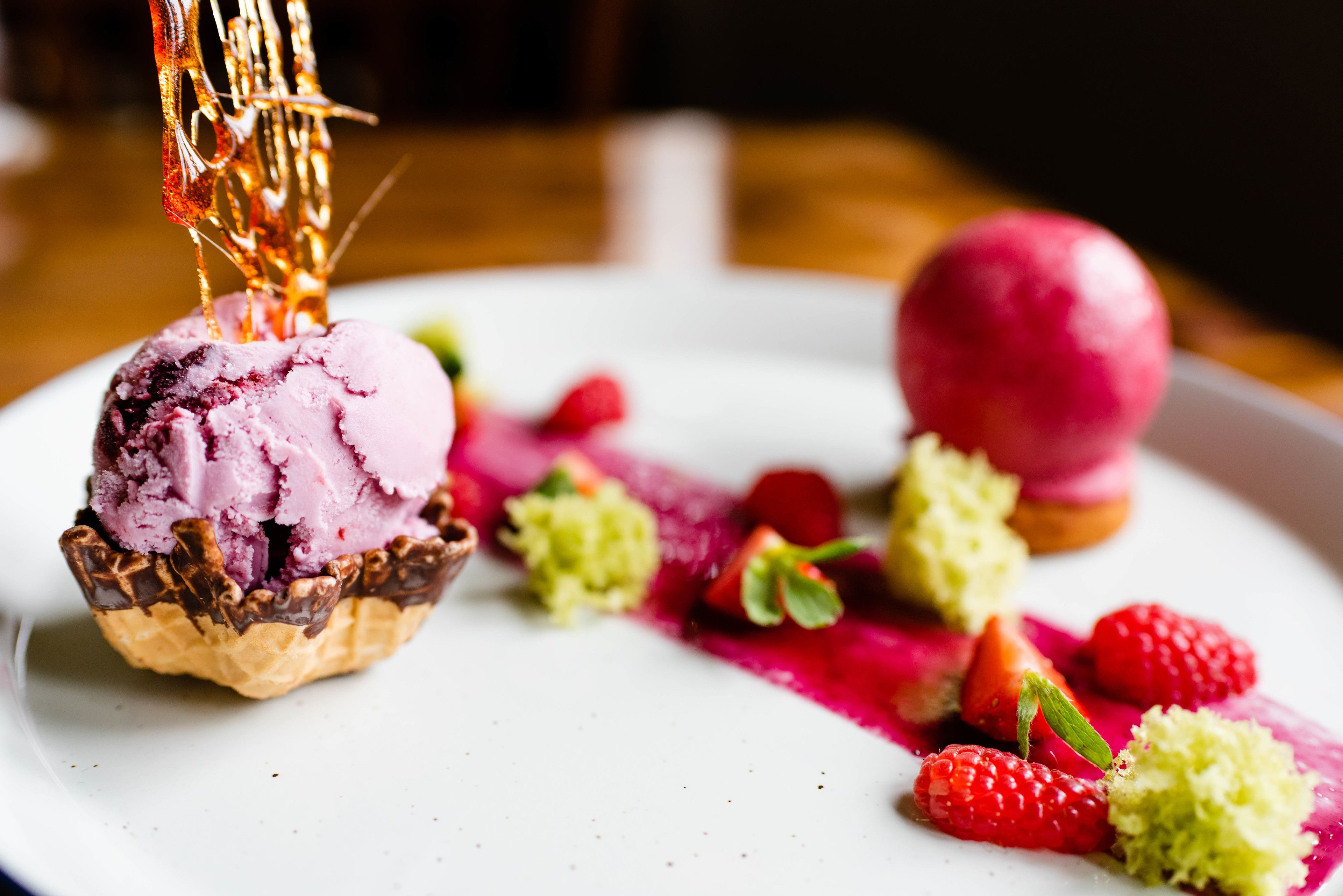 A dessert with ice cream and berries on a plate.