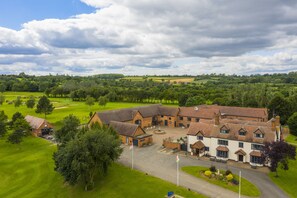 A large, traditional building with multiple rooms, a courtyard, and a golf course in the background. - The Stratford Park Hotel & Golf Club (Stratford-upon-Avon)