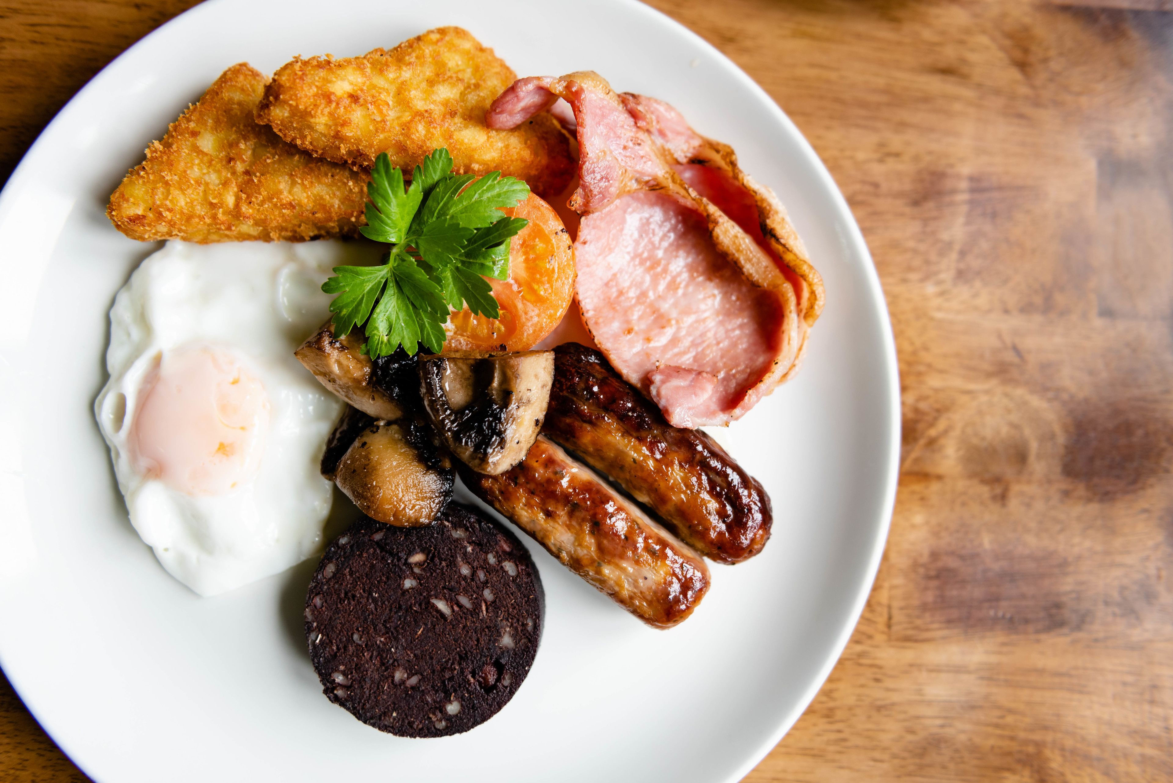 A plate of breakfast food including eggs, sausages, bacon, and black pudding.
