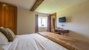 Une chambre à coucher comprenant un lit, une armoire en bois, un bureau, une chaise et un téléviseur fixé au mur.