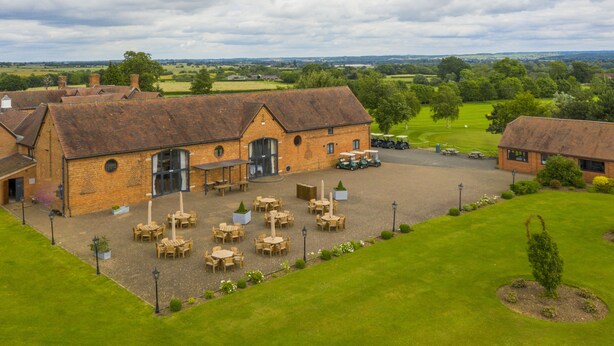 A large brick building with a courtyard, outdoor seating, and a golf cart. - The Stratford Park Hotel & Golf Club (Stratford-upon-Avon)