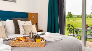 A neatly made bed with a basket of croissants, a coffee pot, and a mug of orange juice. - The Stratford Park Hotel & Golf Club (Stratford-upon-Avon)