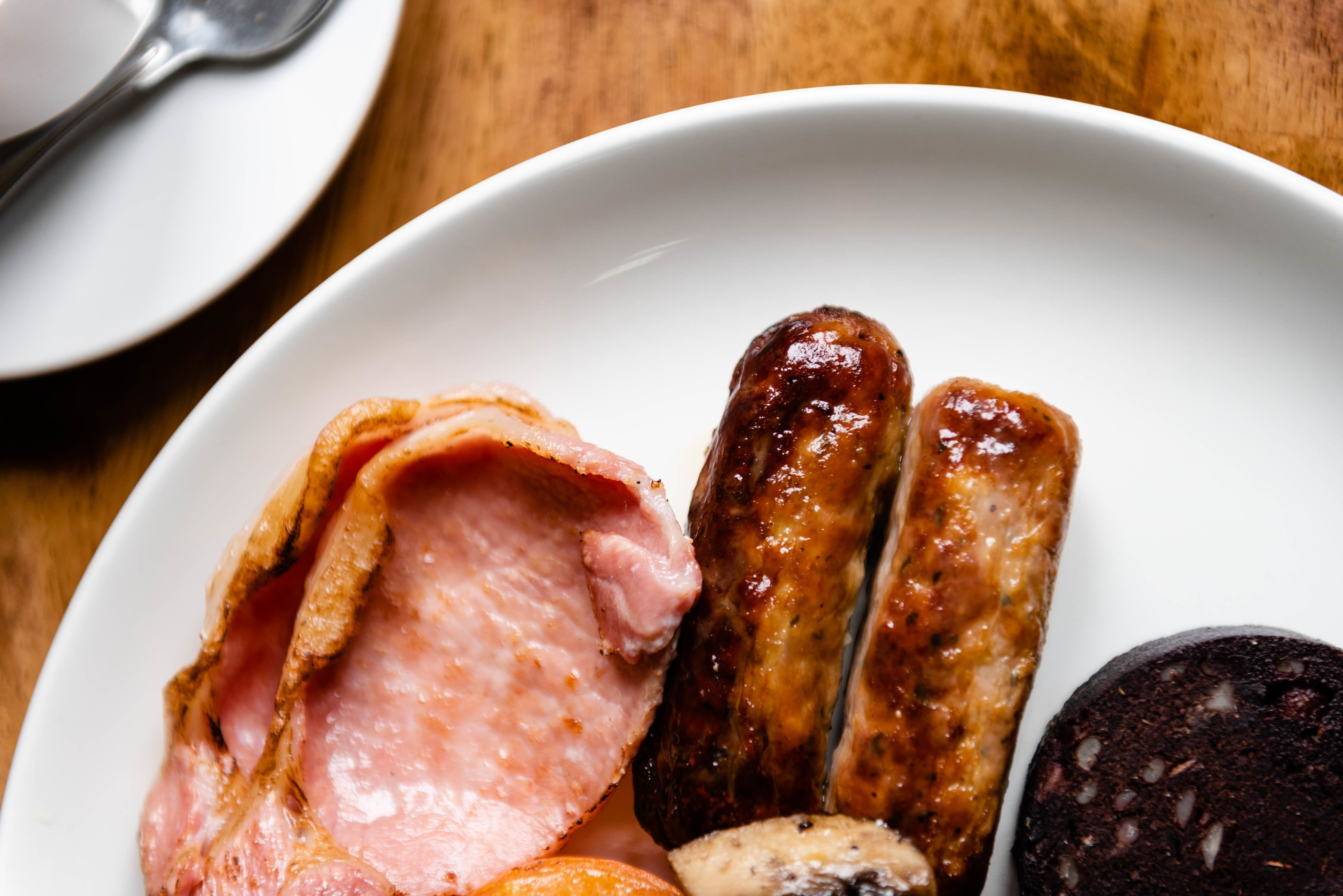 Un plato con diferentes carnes, incluyendo salchichas y una loncha de jamón.