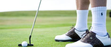 A golf ball on a tee with a golf club nearby.