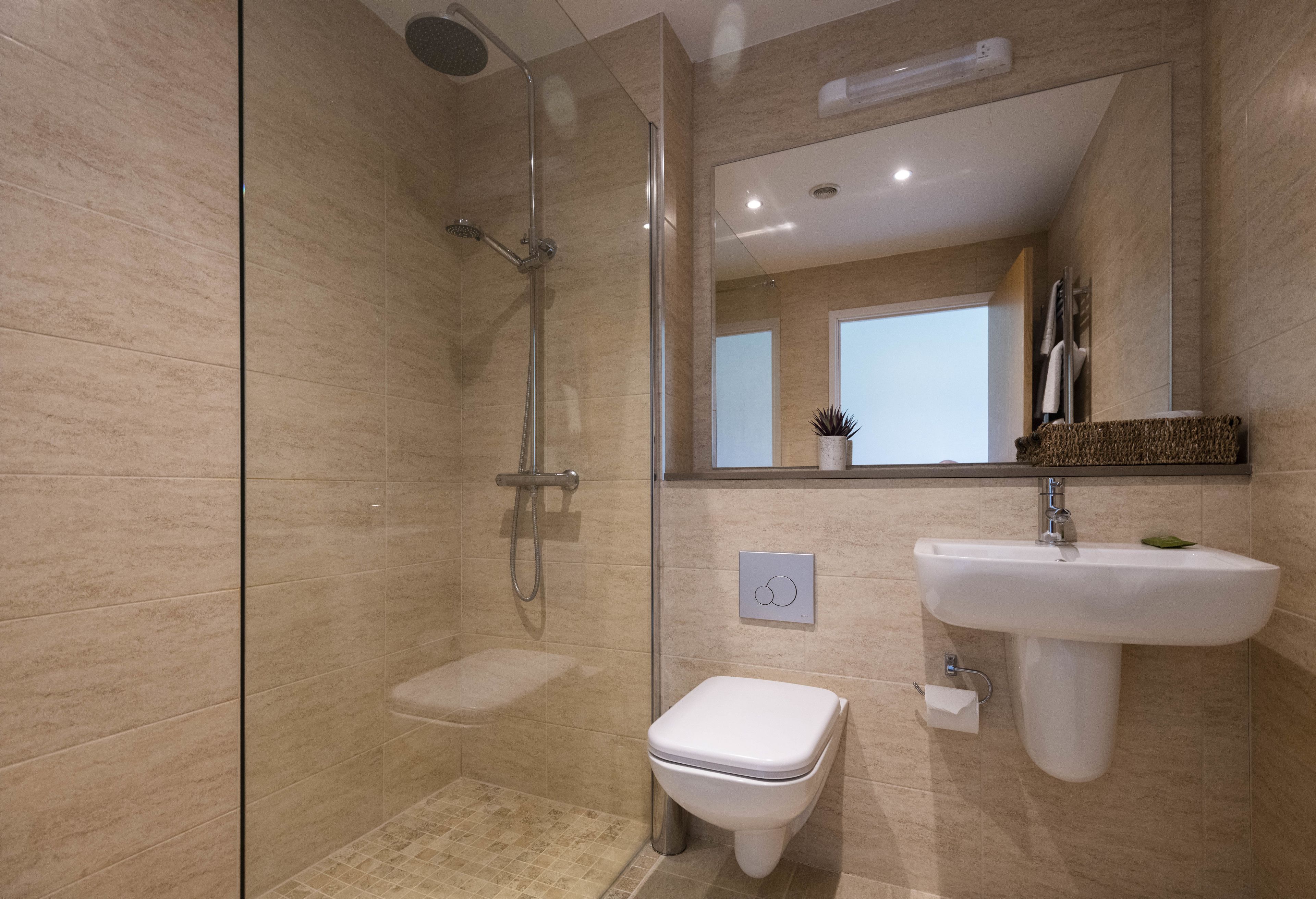 A modern bathroom with a glass-enclosed shower, a white toilet, and a sink with a mirror above.