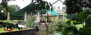 A hotel with outdoor seating, a covered patio, and a pond. - De Wapser Herberg (Wapse)