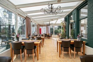 A restaurant with a glass roof, wooden tables, and chairs. - De Wapser Herberg (Wapse)