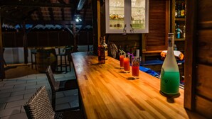 A wooden bar area with a long counter, several bottles, and glasses. - Makare Lagoon Club (Le Vauclin)