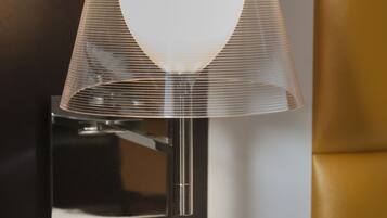 A modern wall-mounted lamp with a clear shade and a metallic base.