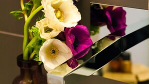 A mirror reflecting a bouquet of flowers with white and purple blooms, placed on a white surface. - DVE Suite Rome (Rome)
