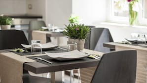 A dining area with tables set for two, featuring a potted plant and a glass of water on the table. - DVE Suite Rome (Rome)