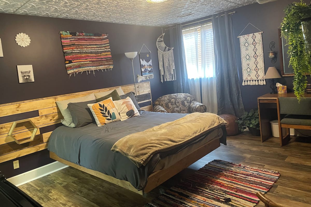 A bedroom with a wooden bed, a colorful rug, and a ceiling with intricate patterns.