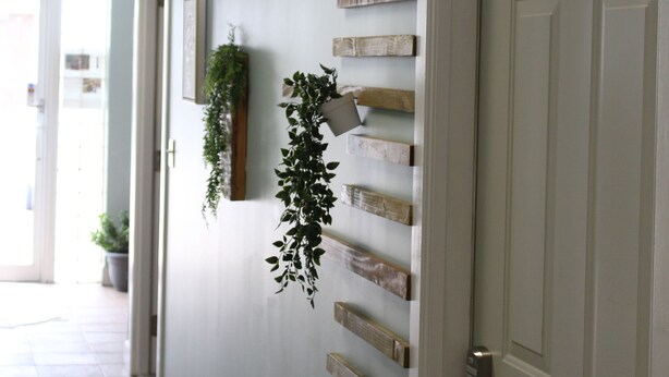 Ein Flur mit hellblau gestrichener Wand, Holzregalen und einer Tür mit der Nummer 2.