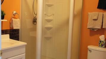 A bathroom with a glass-enclosed shower, a toilet, and a sink with a white countertop.