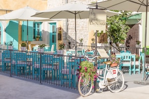 A restaurant with outdoor seating, turquoise chairs, and umbrellas. - Heritage hotel Chersin (Fazana)