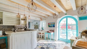 A kitchen with a central island, hanging pendant lights, and a view through a large arched window. - Heritage hotel Chersin (Fazana)